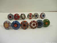 Front view of 12 round porcelain handles arranged in two rows showing diverse floral designs and colors on each handle.