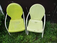 Two vintage metal lawn chairs with white frames against a dark background, showing wear and dirt on yellow and cream seats.