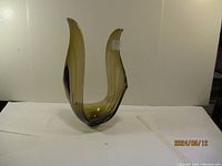 Front view of a tall, curved art glass sculpture with yellow-green and black coloring showing its shape and color.