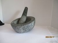 Side view of granite mortar and pestle showing texture and shape.