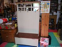 Full view of the hall stand showing the tall back panel with hooks and the storage bench below, situated among other furniture items.