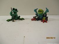 Both frog figurines featured sitting on a white surface, showing overall design and colors.