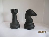 Front view of both chess piece bookends, showing the rook on the left and the knight on the right, both black and about 7 inches tall.