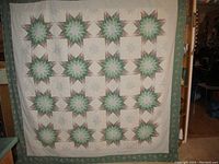 Full front view of large quilt with star pattern and outer green border
