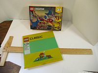 LEGO Creator Fire Dragon set box and green Classic baseplate in packaging with rulers for scale