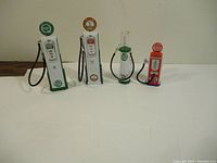 Four mini die cast gas pumps arranged with hoses visible, showcasing height and style variety.