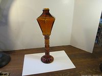 Full view of the 20-inch tall amber glass candle lantern on a wooden surface against a white background.