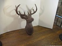 Resin deer head mounted on a wall showing right side profile with detailed antlers and textured surface.