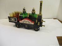 Front-side angle of the vintage train decanter set showing two green glass decanters, shot glasses in the tender, and decorative painted details.