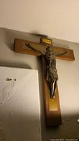 Side angled view of the crucifix showing the metal figure of Jesus mounted on the wooden cross with INRI plaque at top
