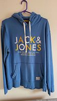 Front view of a blue Jack & Jones hoodie showing logo and drawstrings