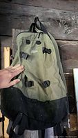 Full front view of the olive green and black Mountain Equipment Co-op backpack showing all straps and top handle.