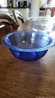 Side view of small blue translucent Pyrex bowl showing depth and smooth rounded shape