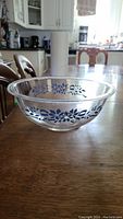 Clear Pyrex bowl on wooden table with blue floral pattern around outside