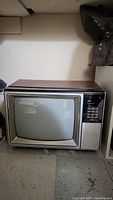 Photo of vintage RCA TV from front angle showing woodgrain top, screen, and control panel