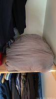 Weighted blanket folded on a wooden shelf in a closet, showing its taupe color and soft texture.