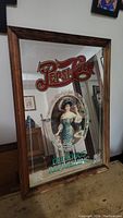 Front angle photo showing entire wooden-framed mirror with central painted vintage Pepsi-Cola image and branding text