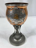 Full view of the 9-inch tall copper cladded chalice showing the silver-tone metal base and ornate stem with floral detail, and the plaque inscribed for the 21st Annual Schoolboy Meet 1910 team race with raised horse head emblem.