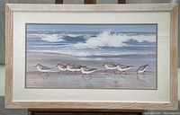Full framed artwork of sandpipers walking on shore with waves in background