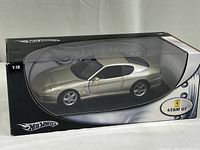 Front and side view of large Hot Wheels Ferrari 456M GT model car in original box, showcasing metallic silver color and packaging details.
