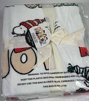 Folded and sealed Peanuts VelvetSoft throw blanket in original plastic bag with cream ribbon.