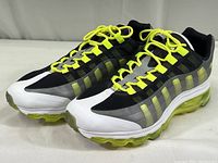 Front and side view of shoe pair showing yellow laces, black and grey mesh upper, white toe and midsole, and yellow translucent air sole unit.