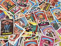 Pile of various Garbage Pail Kids trading cards showing colorful and detailed cartoon characters with humorous grotesque themes.
