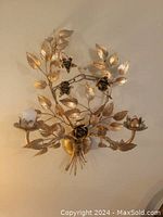 Front view of the gold-finish metal floral wall candle sconce with three candle holders.