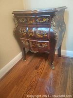 Front left angle view of the antique Louis XV style bombe chest of drawers showing curved front with marquetry inlay and ormolu hardware.