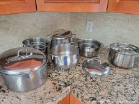 Full view of all pots and lids arranged on countertop showing variety in sizes and presence of lids.