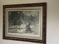 Framed black and white print of Edward Percy Moran's painting "A Friend in Need," showing the entire framed artwork on a wall.