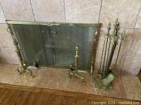 Full view of the vintage brass fireplace screen, brass andirons, and fireplace tool set arranged on the fireplace hearth.