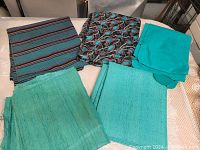 Full view of all five fabric remnants laid out showing colors and patterns, turquoise solids and prints.