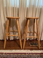 Front view showing two wooden stools with carved turned legs and strong horizontal supports.