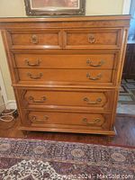 Front view of the maple wood tallboy dresser showing all six drawers and antique brass hardware.