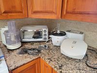 Corner kitchen countertop with all small appliances displayed: food processor, toaster oven, crockpot, toaster, grill.
