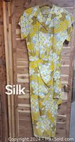 Full front view of the 1940s style silk dress hanging on a wooden door, showing the full length and graphic print.