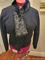Front view of black ribbed wool women's suit jacket with glossy black mink asymmetrical scarf collar on a dress form.
