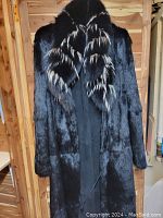 Front view of long black mink fur coat with dual fur shawl collar. Fur is glossy and the collar has a mix of black and white tipped fur features.