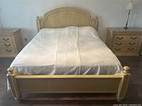 Front view of the Bassett king size bed with white blanket, showing padded headboard and footboard with light wood frame and matching nightstands on each side.