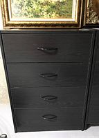 Front view of laminated dresser showing four drawers with black handles and wood grain finish.