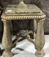 Front angled view of a wood frame end table with a beige and brown stone top, showing detailed carved legs with leaf motifs and a twisted rope border under the stone surface.