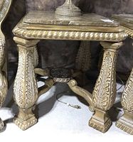 Close-up photo of carved wood legs and stone top of end table showing detailed leaf and rope designs and square stone surface.
