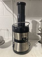 Full view of Jack LaLanne Power Juicer Prestige on shelf, showing entire juicer including chute and metal locking arm