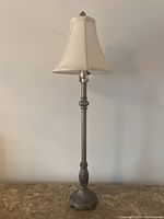 Full view of table lamp with beige fabric shade and cast resin base.