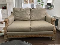 Front view of the love seat displaying beige cushions and carved wooden frame.