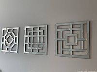 Front view of three decorative beveled glass mirrors hung side by side on a wall, showing their geometric lattice patterns.