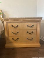 Front view of the nightstand showing three drawers with twisted metal handles and wood veneer finish.