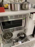 One drawer with assorted pots and pans including large stainless steel pots and frying pans.