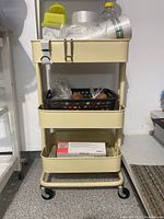 Metal cart with three shelves and items on shelves.